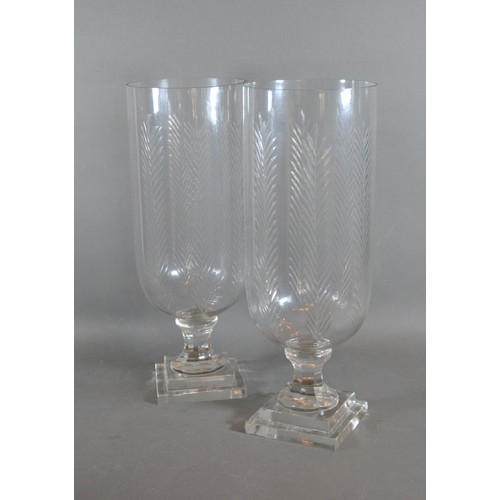 11 - A pair of cut glass storm vases with square pedestal bases, 40cms tall