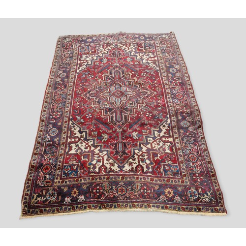 288 - A North West Persian woollen carpet with a central medallion within an allover design upon a red, bl... 