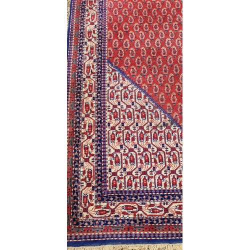 290 - A North West Persian Woollen Carpet with an all over design upon a red, blue and cream ground within... 