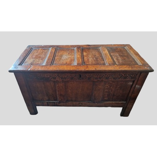 324 - An 18th Century Oak Coffer, the hinged top above a carved frieze and three panel front flanked by st... 