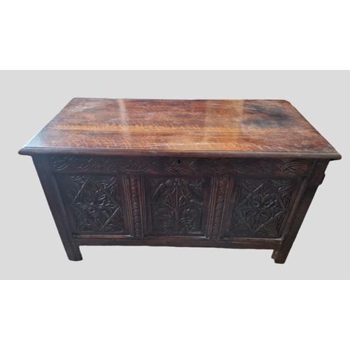 325 - An 18th Century Oak Coffer, the hinged plank top above a carved frieze and three carved panels, the ... 