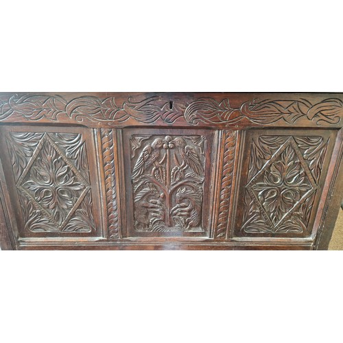 325 - An 18th Century Oak Coffer, the hinged plank top above a carved frieze and three carved panels, the ... 