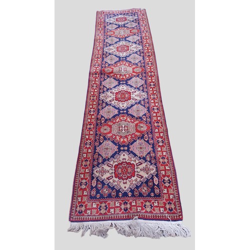 333 - A North west Persian woollen runner with an all over design upon a blue, red and cream ground within... 