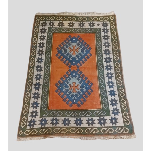 335 - A Turkish woollen rug with two medallions upon a terracotta, blue and cream ground within multiple b... 