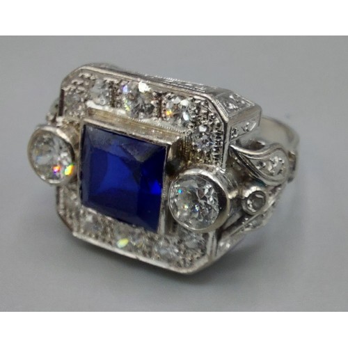 148 - A white metal Synthetic Sapphire and diamond cluster ring set with a central square synthetic Sapphi... 