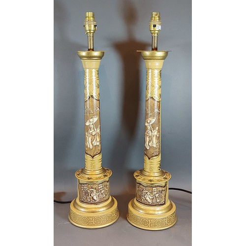 281 - A pair of Toleware table lamps, each with gilded decoration with figures upon a mustard ground, 60cm... 