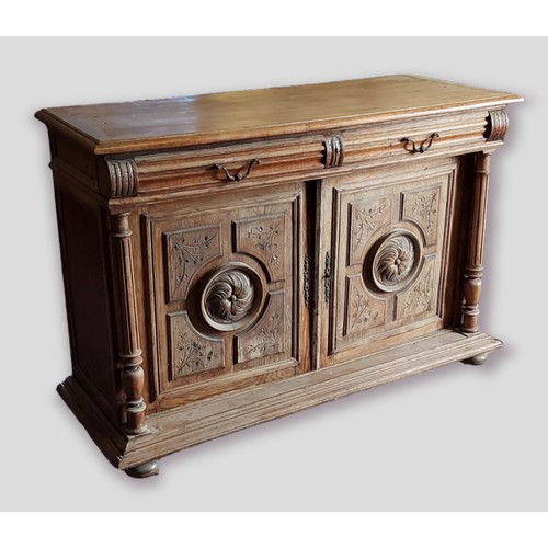 374 - A French oak dresser base, the moulded top above two drawers and two carved panel doors flanked by t... 