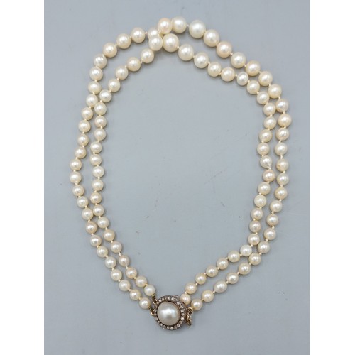 141 - A graduated double row pearl necklace, the clasp set with a large pearl surrounded by diamonds, 37cm... 