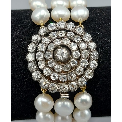 149 - A triple row pearl choker, the large clasp set with a central Diamond surrounded by three tiers of D... 