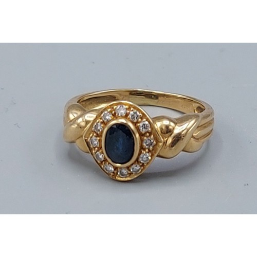 174 - An 18ct gold ring set with a central oval sapphire surrounded by diamonds, 3.6gms, ring size J