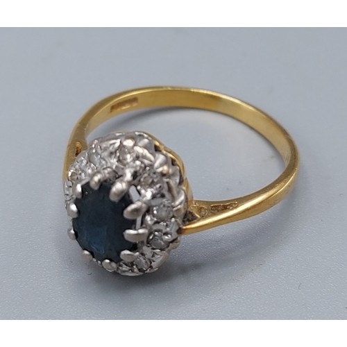 193 - An 18ct gold sapphire and diamond cluster ring with a central oval sapphire surrounded by diamonds, ... 