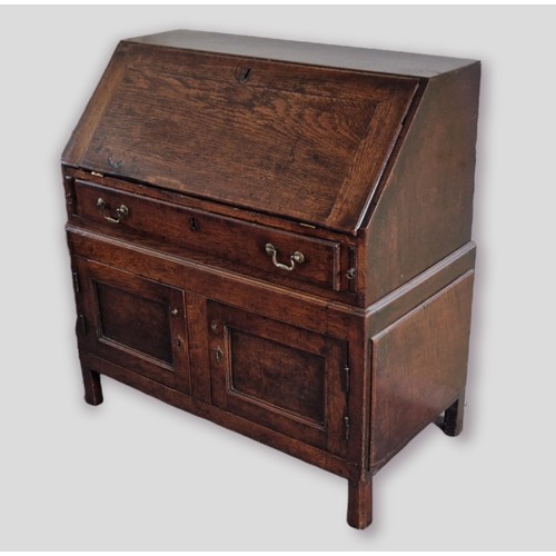 440 - A 19th Century oak bureau, the fall front enclosing a fitted interior above a drawer and two cupboar... 