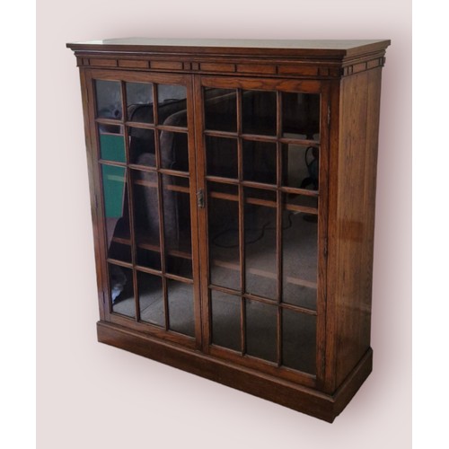 329 - An oak bookcase, the moulded top above two glazed doors, raised upon a plinth, 108cms wide, 38cms de... 