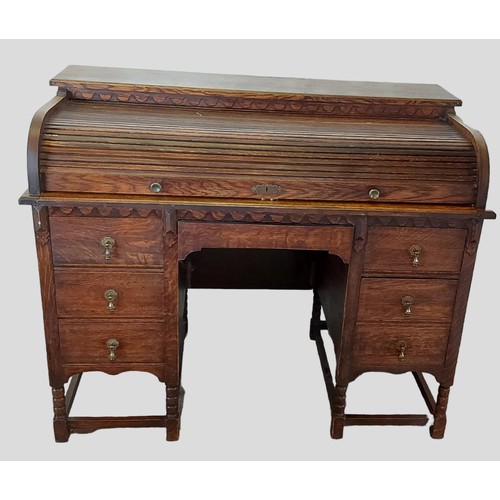 433 - An early 20th Century oak roll top desk with seven drawers, brass drop handles and raised upon turne... 