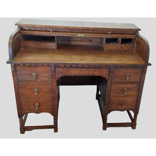 433 - An early 20th Century oak roll top desk with seven drawers, brass drop handles and raised upon turne... 