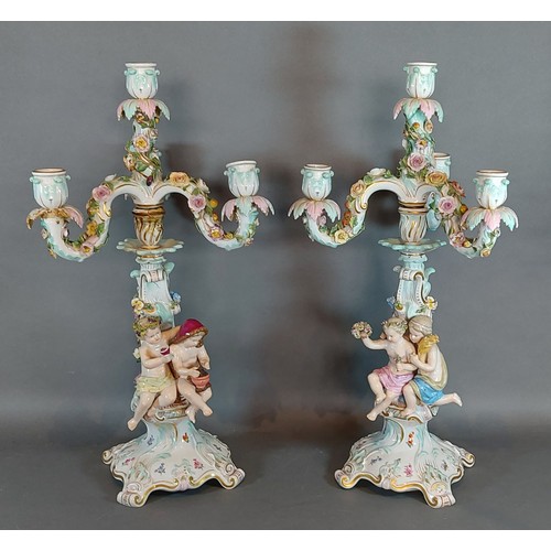 63 - A pair of Meissen porcelain candelabrum, each mounted with Putti decorated in polychrome enamels and... 