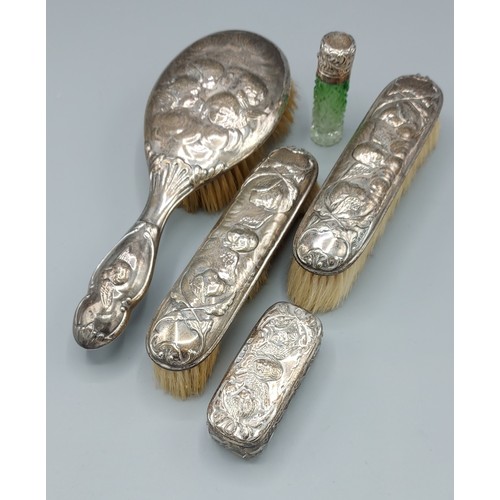 112 - A silver backed four piece dressing table set comprising three brushes and a glass bottle, all decor... 