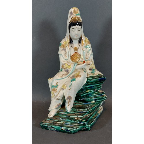 16 - A Chinese porcelain figure in the form of Guan Yin holding a scroll upon green glazed rocky base, 27... 