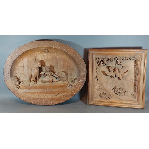 250 - A Black Forest carved oval panel depicting a child with two dogs, 48cms X 62cms together with anothe... 