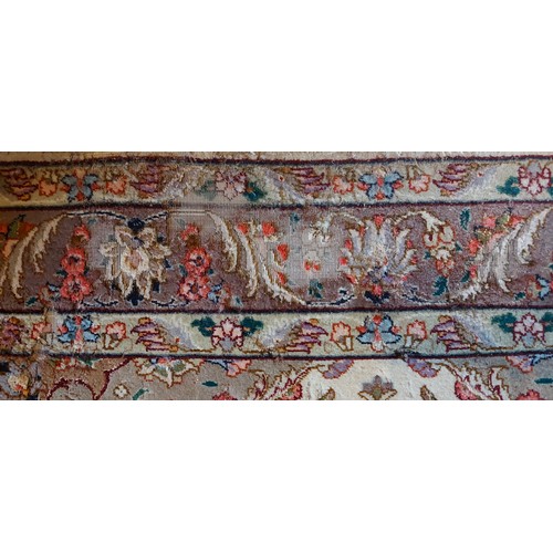 303 - An Indian Silk Rug with a central medallion within an all over design upon a cream, blue and red gro... 