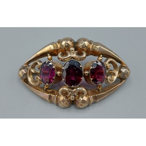 191 - A Victorian brooch of pierced design and set with three Amethysts, 5.5cms long