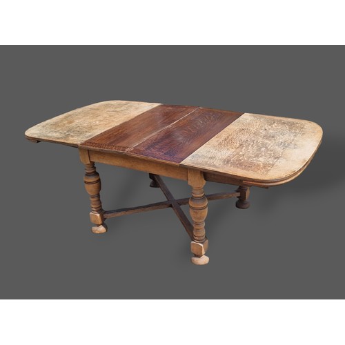 256 - A 1930's oak drawer leaf extending dining table raised upon turned legs with stretchers, together wi... 