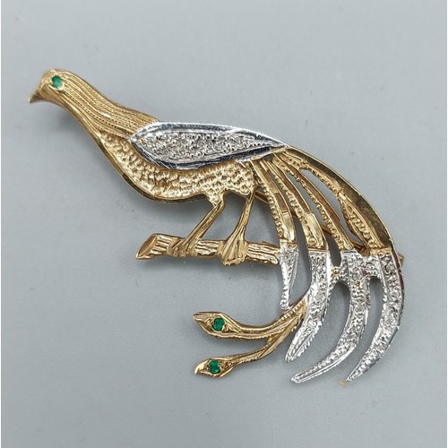 150 - A 9ct gold brooch in the form of a peacock upon a branch, set with diamond and emeralds, 4cms long