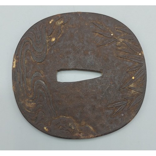 255 - An early Japanese Tsuba decorated in relief with a Tiger amongst bamboo highlighted with gilt, 8cms ... 