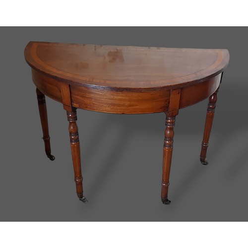 391 - A Regency mahogany demi-lune side table, the crossbanded and reeded top above turned tapering legs w... 