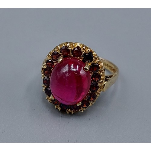 60 - A 9ct gold ring with Cabochon stone surrounded by Garnets, 6.1gms, ring size L