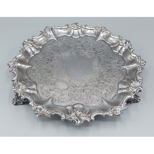 121 - A Victorian silver salver with embossed and engraved decoration raised upon three scroll feet, Londo... 