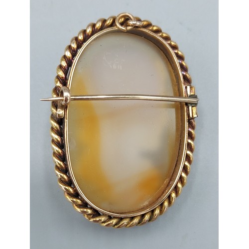 130 - A yellow gold mounted carved hardstone cameo brooch depicting a classical female, 3.5cms by 5cms