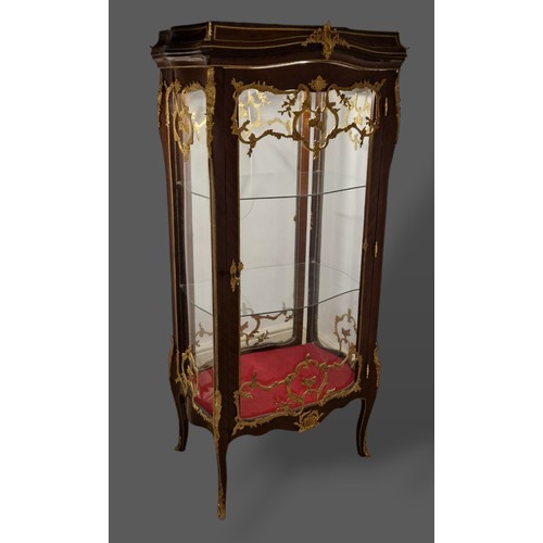 467 - A French large Vitrine with a serpentine glazed double sided door enclosing glass shelves raised upo... 