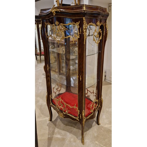 468 - A French large Vitrine with a serpentine glazed double sided door enclosing glass shelves raised upo... 