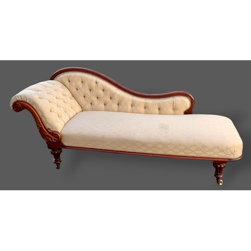 205 - A Victorian mahogany Chaise Lounge, with a carved scroll and buttoned end raised upon turned reeded ... 