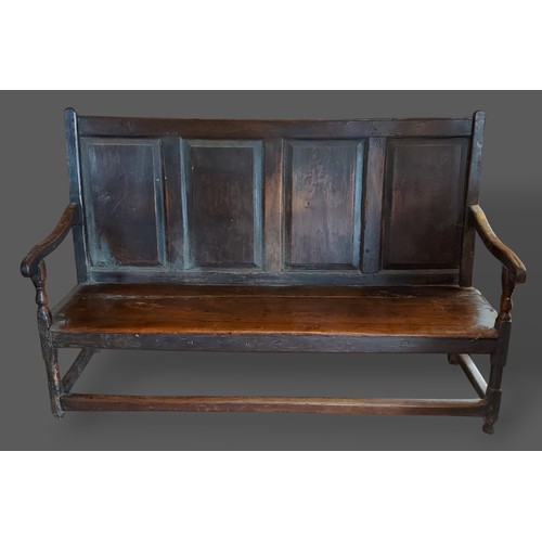 209 - A George III oak Settle with a four panel back above a panel seat and raised upon turned legs with s... 