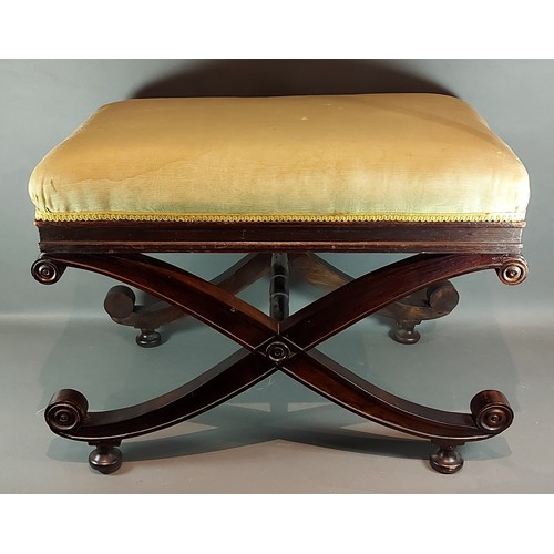 214 - A mahogany cross over footstool with an upholstered top above shaped supports