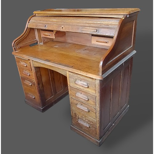 272 - A Circa 1930's oak roll top desk with a shaped tambor above various pedestal drawers, 121cms wide, 7... 