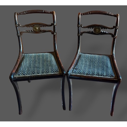 276 - A pair of Regency brass mounted side chairs, each with a pierced carved rail back raised upon sabre ... 