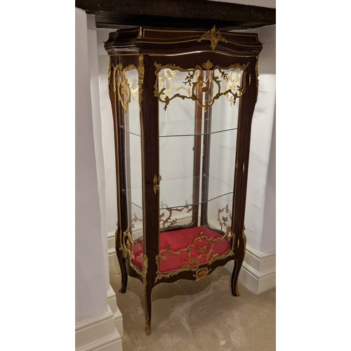 295 - A French large Vitrine with a serpentine glazed double sided door enclosing glass shelves raised upo... 