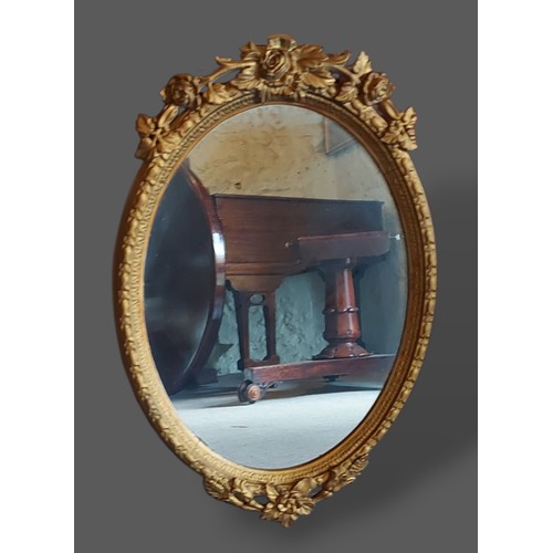 246 - A gilt framed oval wall mirror with foliate cresting, 82cms x 54cms