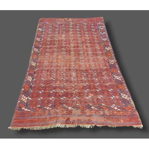 208 - A Tekke woollen rug with rows of Guls upon a red ground within multiple borders, 208cms x 328cms