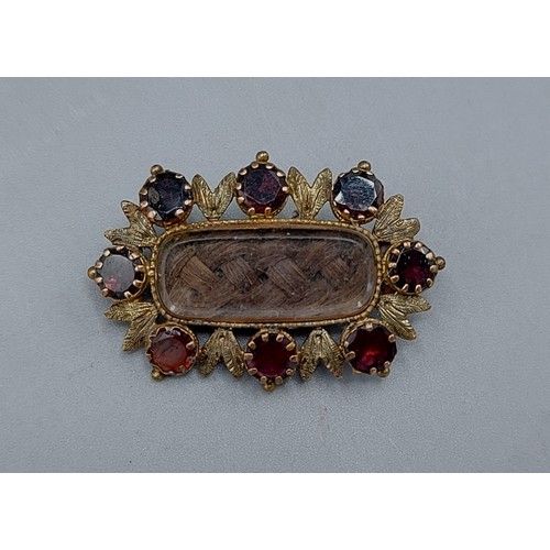 125 - A Victorian yellow metal mourning brooch set with eight garnets, 2cms by 2.5cms, 3.8gms