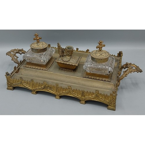 200 - A 19th Century gilt metal inkstand with two glass inkwells and central candlestick and with shaped e... 