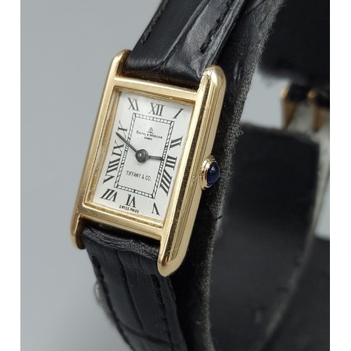 74 - A 14ct gold cased ladies wristwatch by Baume and Mercier retailed by Tiffany and Co. with leather st... 