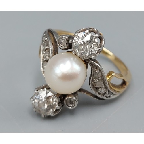 84 - A gold ring set with a central Pearl flanked by two Diamonds within a Diamond mounted scroll setting... 
