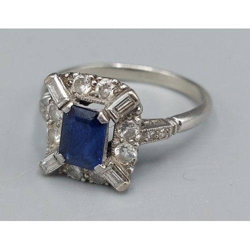 94 - An 18ct gold ring set with a rectangular Sapphire surronded by Diamonds, Diamond baguette corners an... 