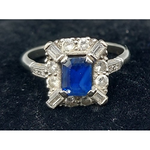 94 - An 18ct gold ring set with a rectangular Sapphire surronded by Diamonds, Diamond baguette corners an... 