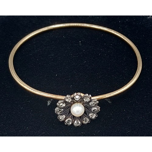 177 - A gold bangle set with a central Pearl surrounded by Diamonds of flower head form, 9.9gms
