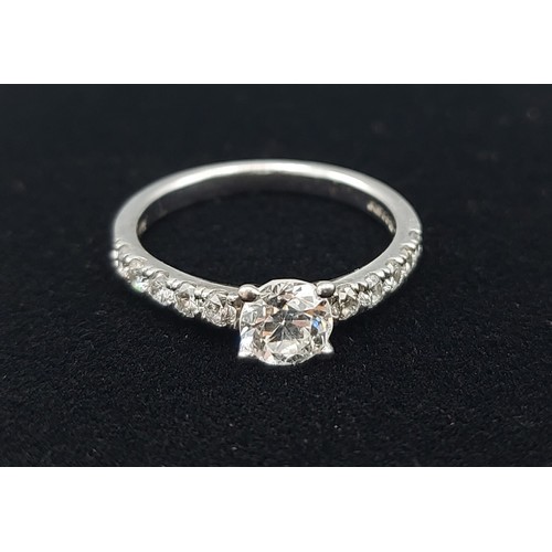 159 - An 18ct gold Solitaire Diamond ring, the claw set Diamond flanked with Diamond shoulders